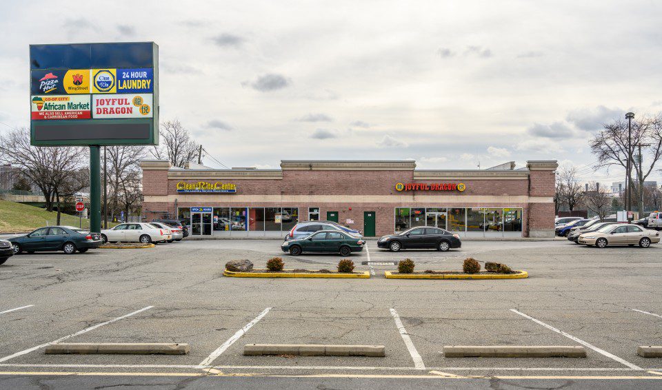 Exterior view of a strip mall with cars parked in front.