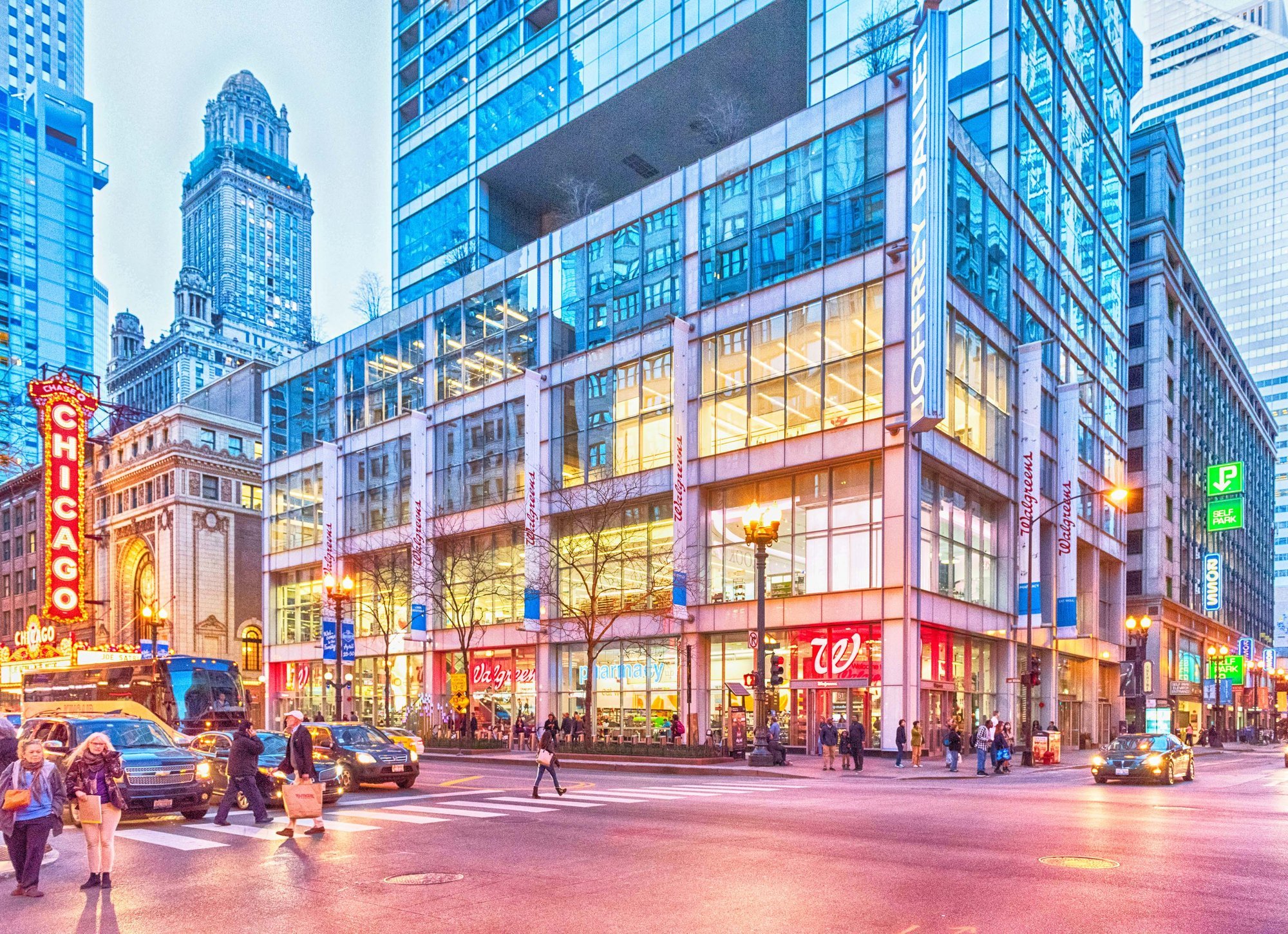 City street scene at dusk with modern buildings and pedestrians.