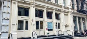 White cast-iron building with three entrances and "Alex Woo" signage.