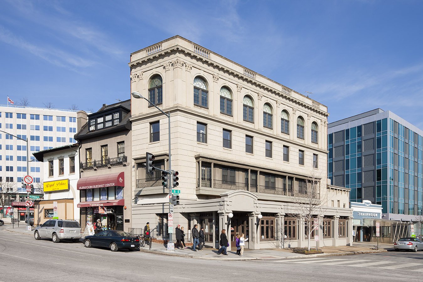 A large, light-beige stone building on a city street corner.