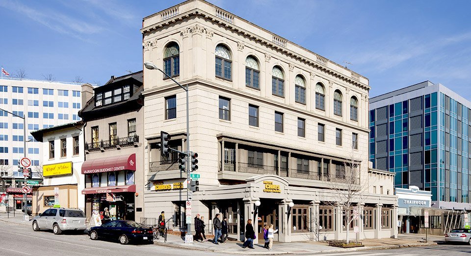 A large, light-beige multi-story building on a city street corner.