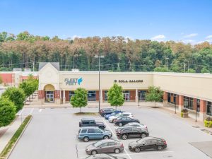Exterior view of a strip mall with cars in the parking lot.