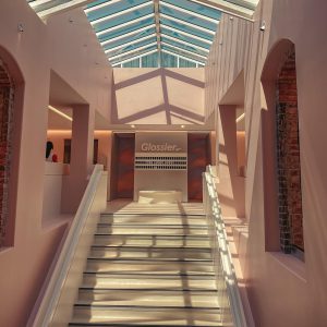 Interior view of a light pink building with a glass skylight and staircase.