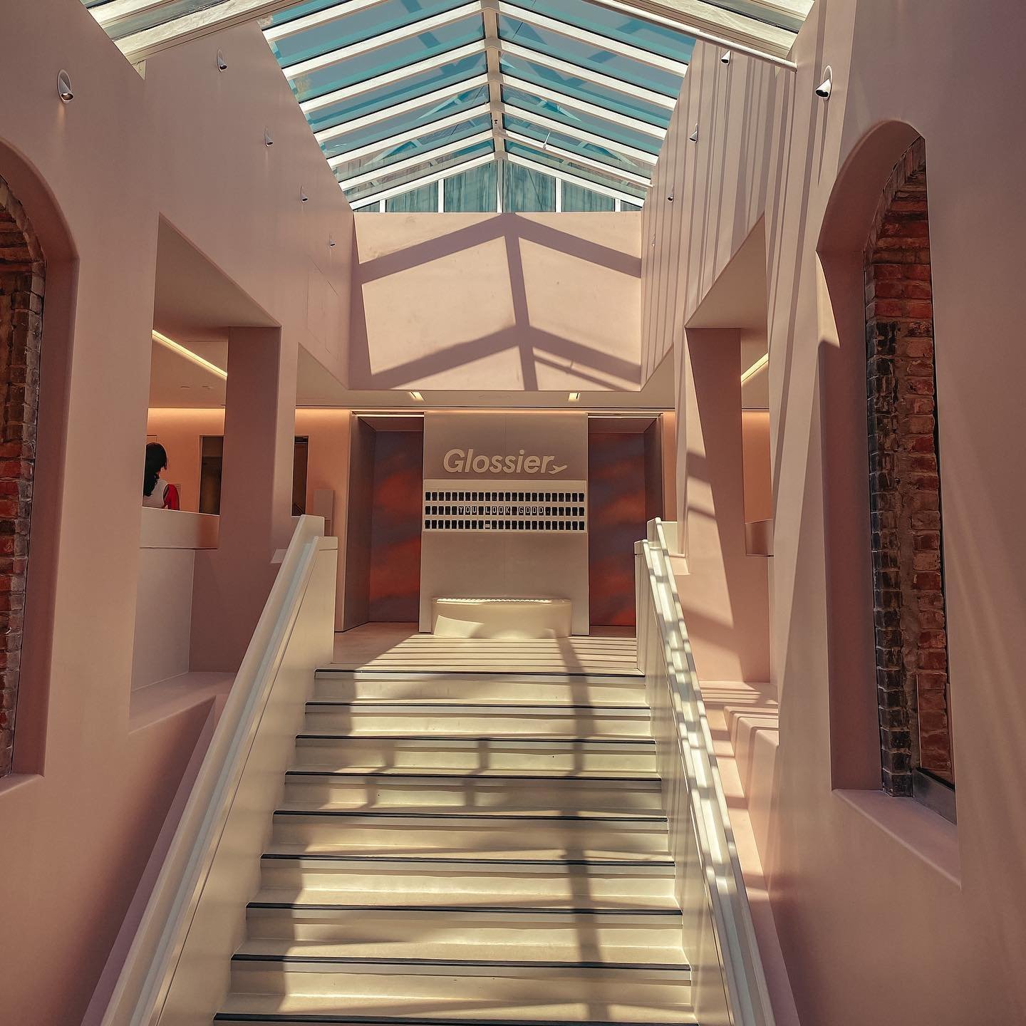 Interior view of a light pink building with a glass skylight and staircase.