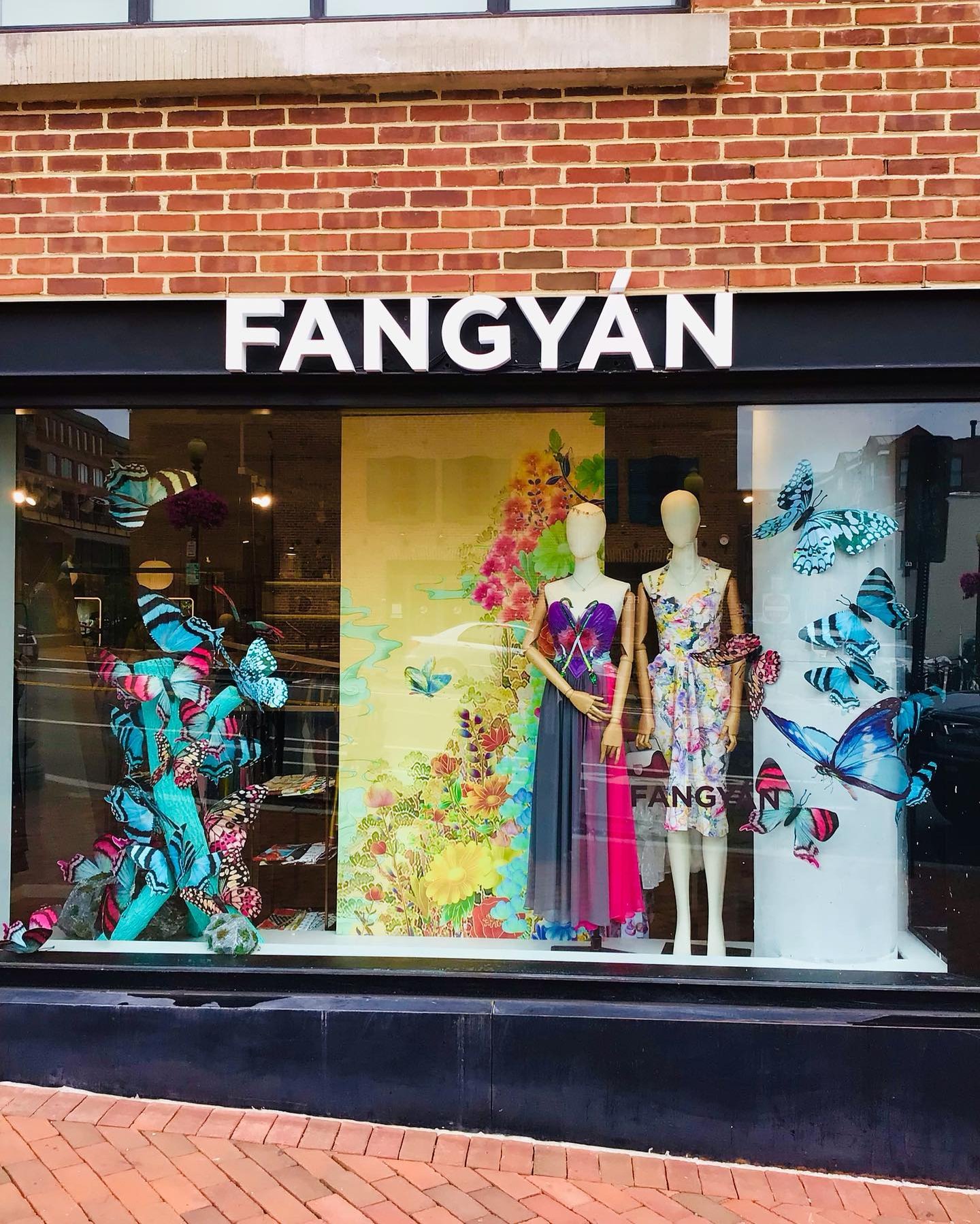 Fangyan boutique storefront window display with mannequins and colorful artwork.