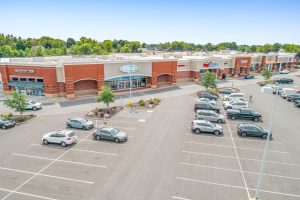 Exterior view of a strip mall with cars in the parking lot.