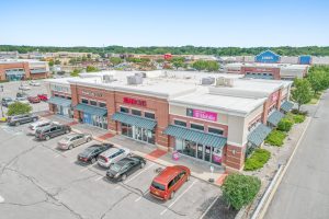 Aerial view of a strip mall with several businesses and a parking lot.