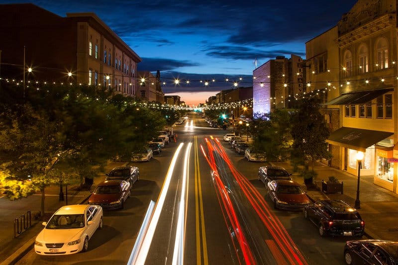 Nighttime street scene with light trails from moving cars.