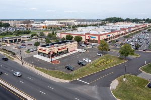 Aerial view of a shopping center with parking lot and roadway.