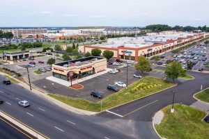 Aerial view of a shopping center with parking lot and businesses.