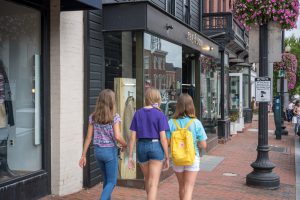 Three girls walking past a storefront.