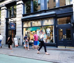 People shopping outside a clothing store in a city.