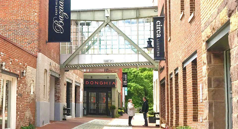 Couple talking in a brick alleyway with shops and a glass walkway overhead.