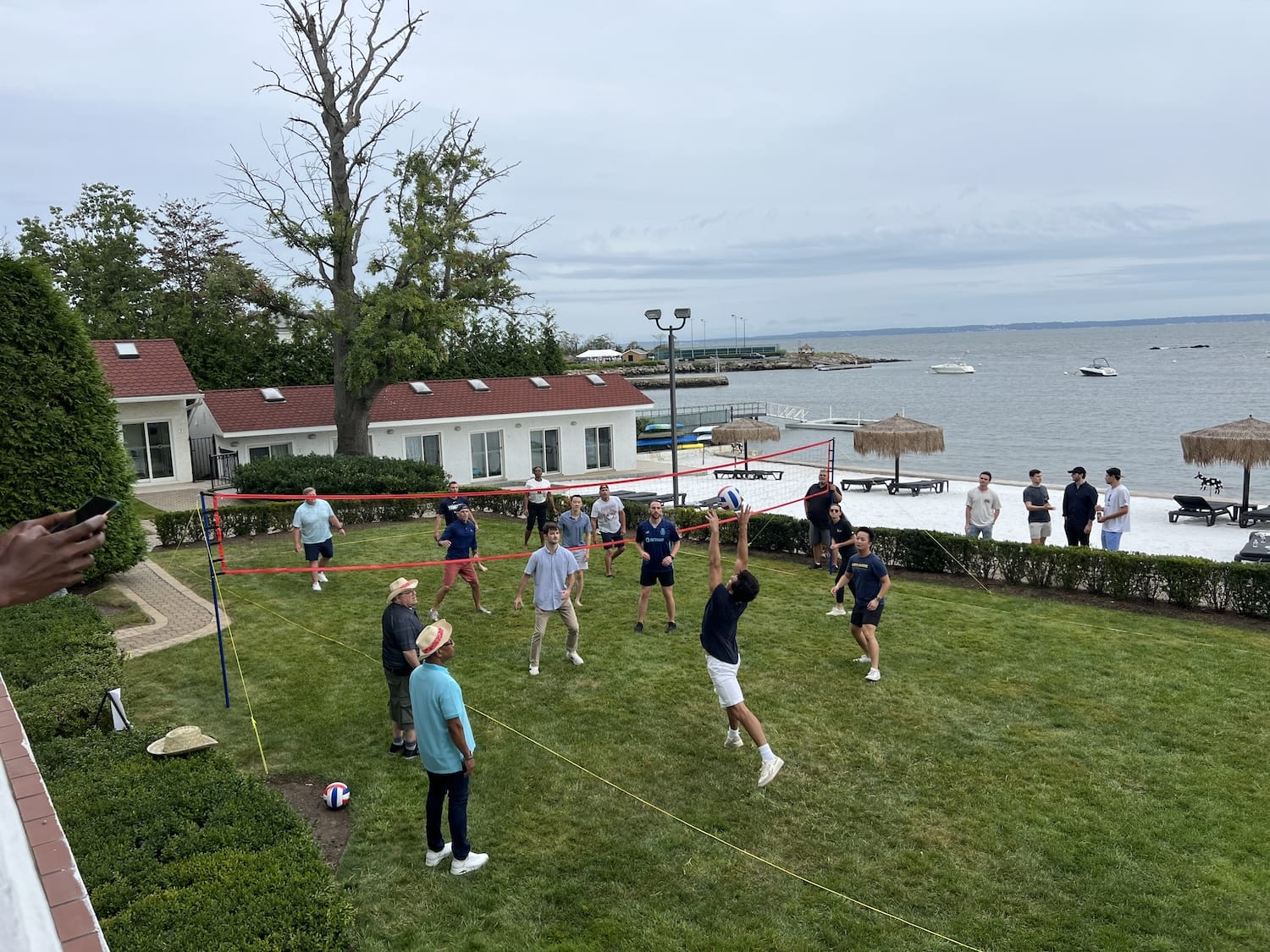 Group of people playing soccer on a grassy field near the water.