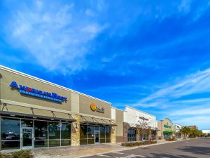 Row of storefronts under a bright blue sky.