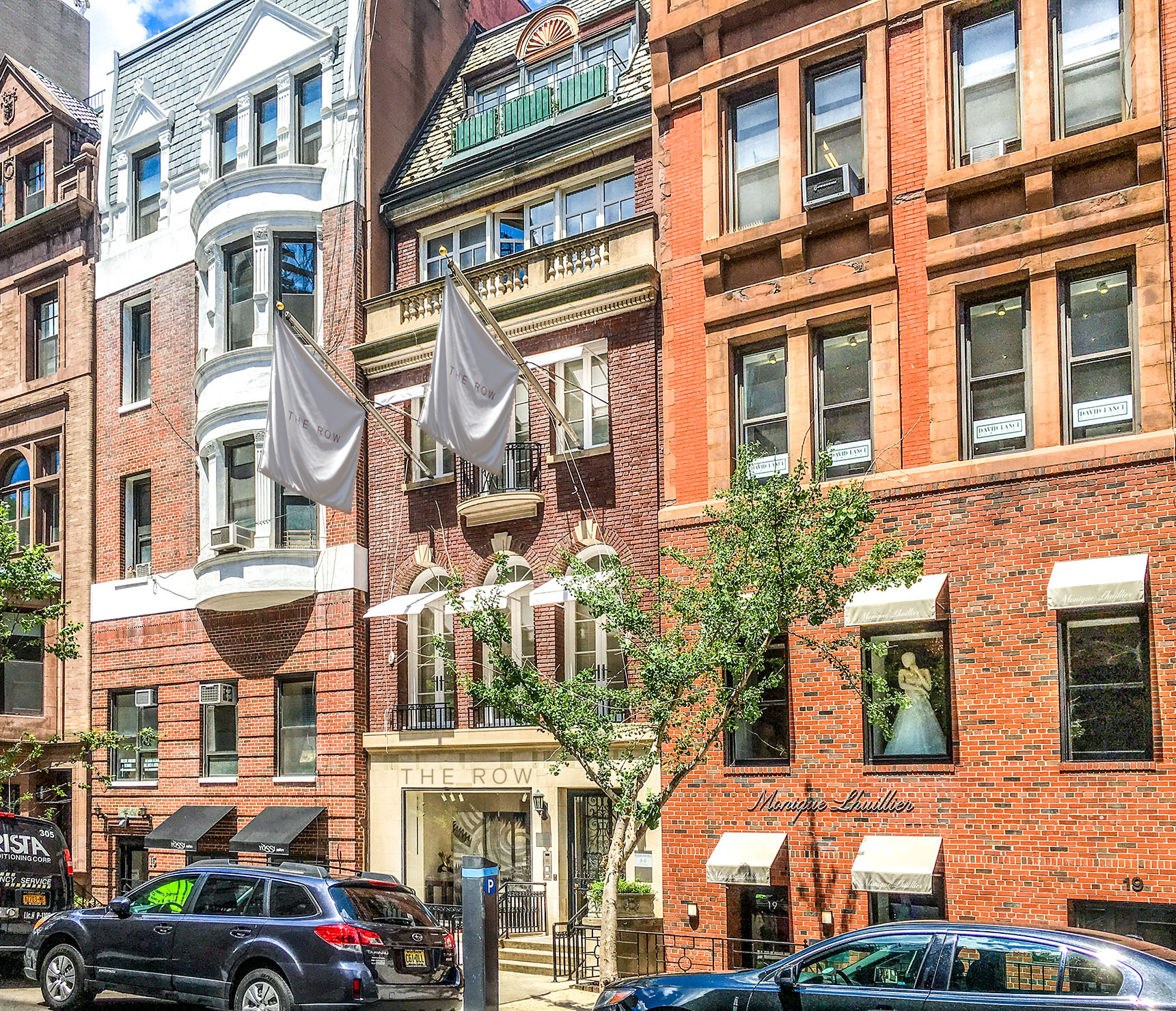 A row of brick townhouses, one with a wedding dress visible in the window.