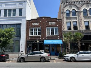 Two-story brick commercial building with blue awning.