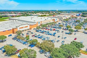 Aerial view of a large retail shopping center parking lot with a Hobby Lobby store.