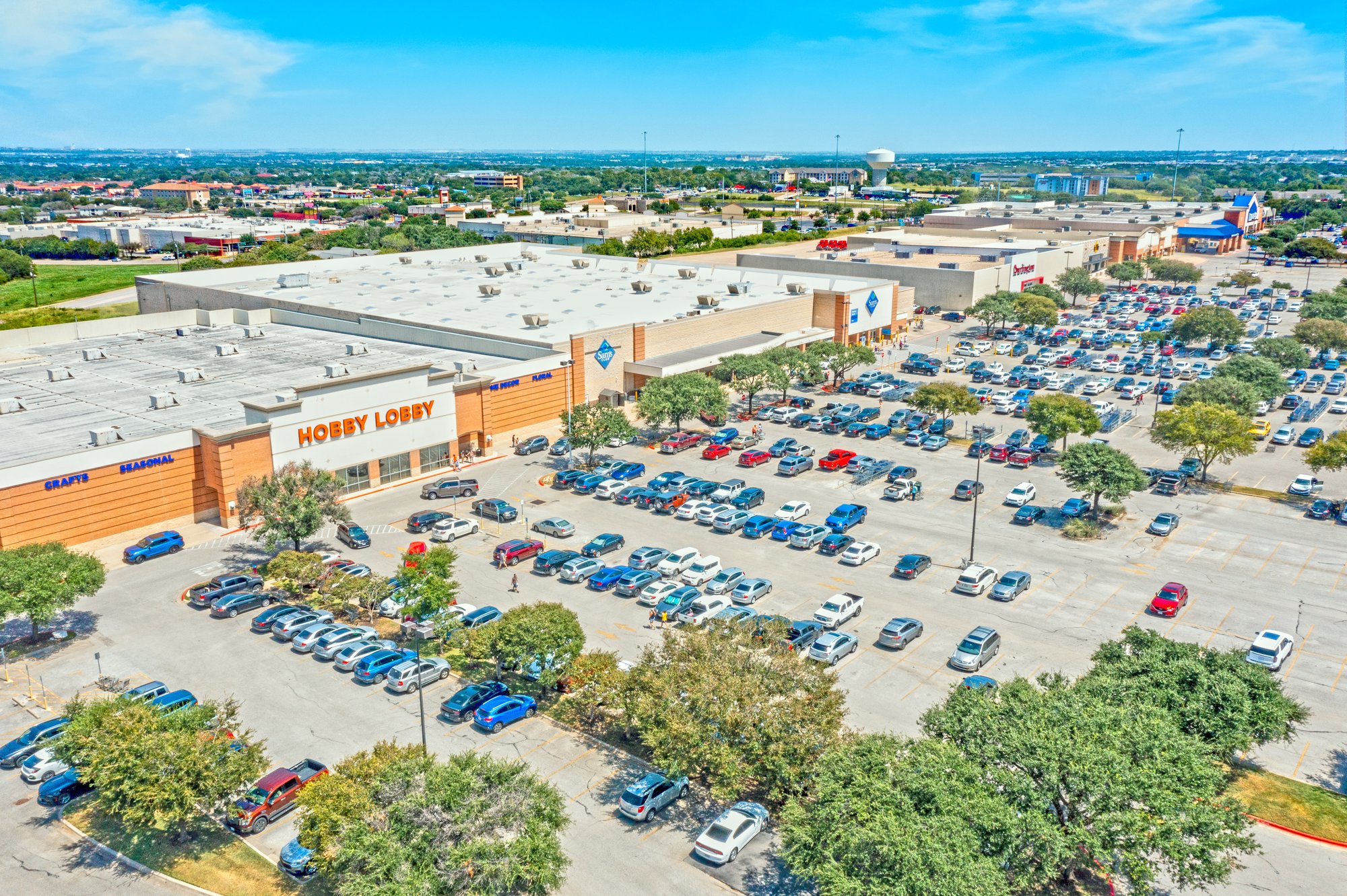 Aerial view of a large retail shopping center parking lot with a Hobby Lobby store.