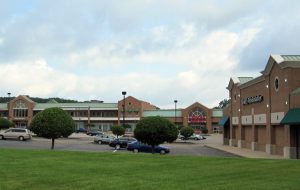 Exterior view of a shopping center with brick buildings and a parking lot.
