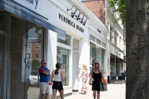 Veronica Beard storefront on a sunny street with pedestrians.