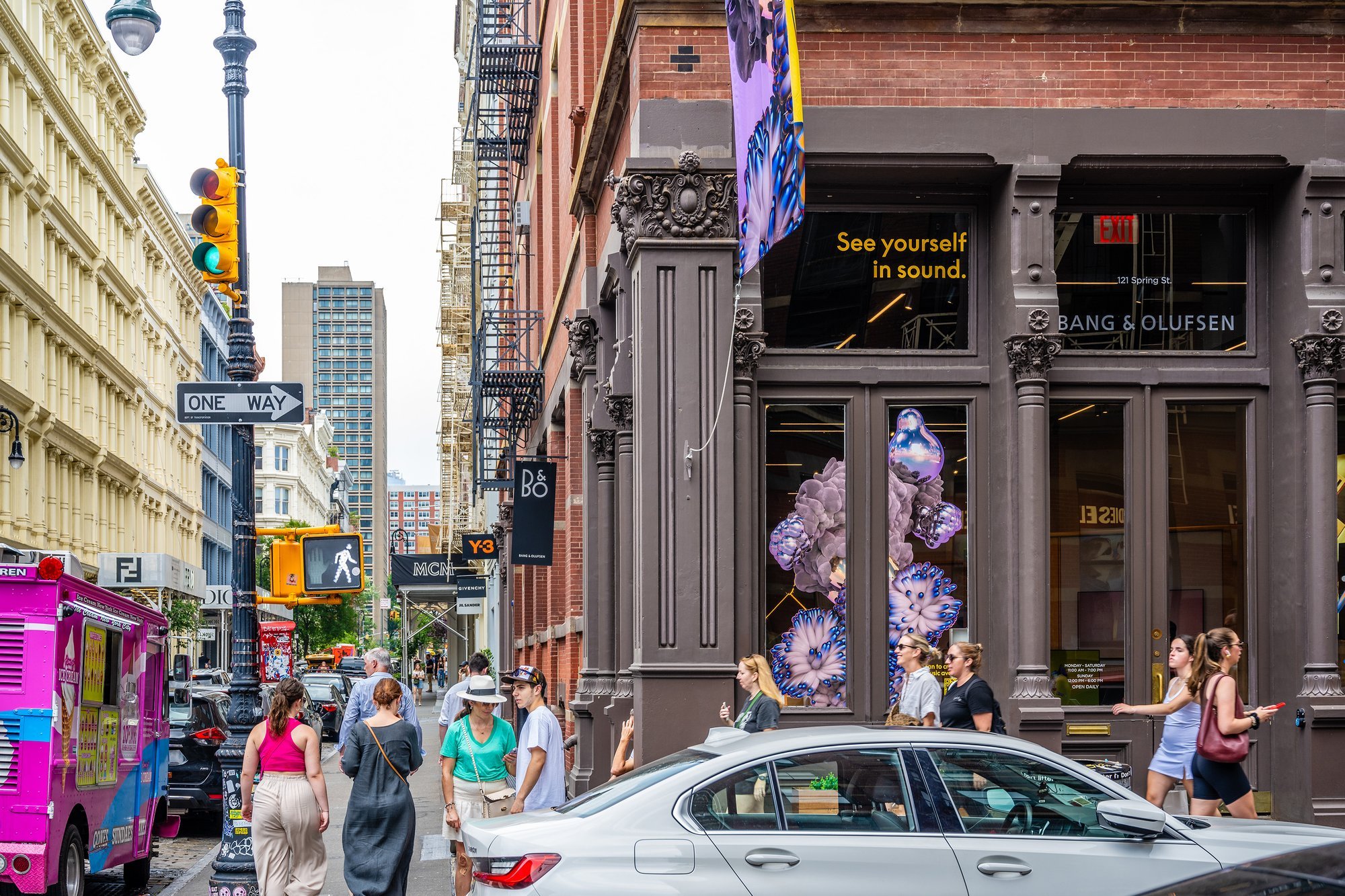 Busy city street corner with pedestrians and a building displaying artwork.