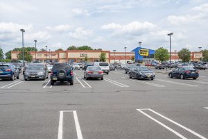 A mostly full parking lot in front of a strip mall with a Best Buy visible.