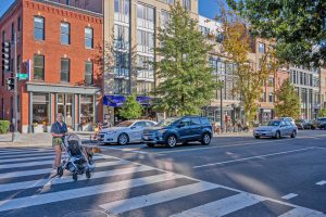 City street scene with pedestrians and cars at a crosswalk.