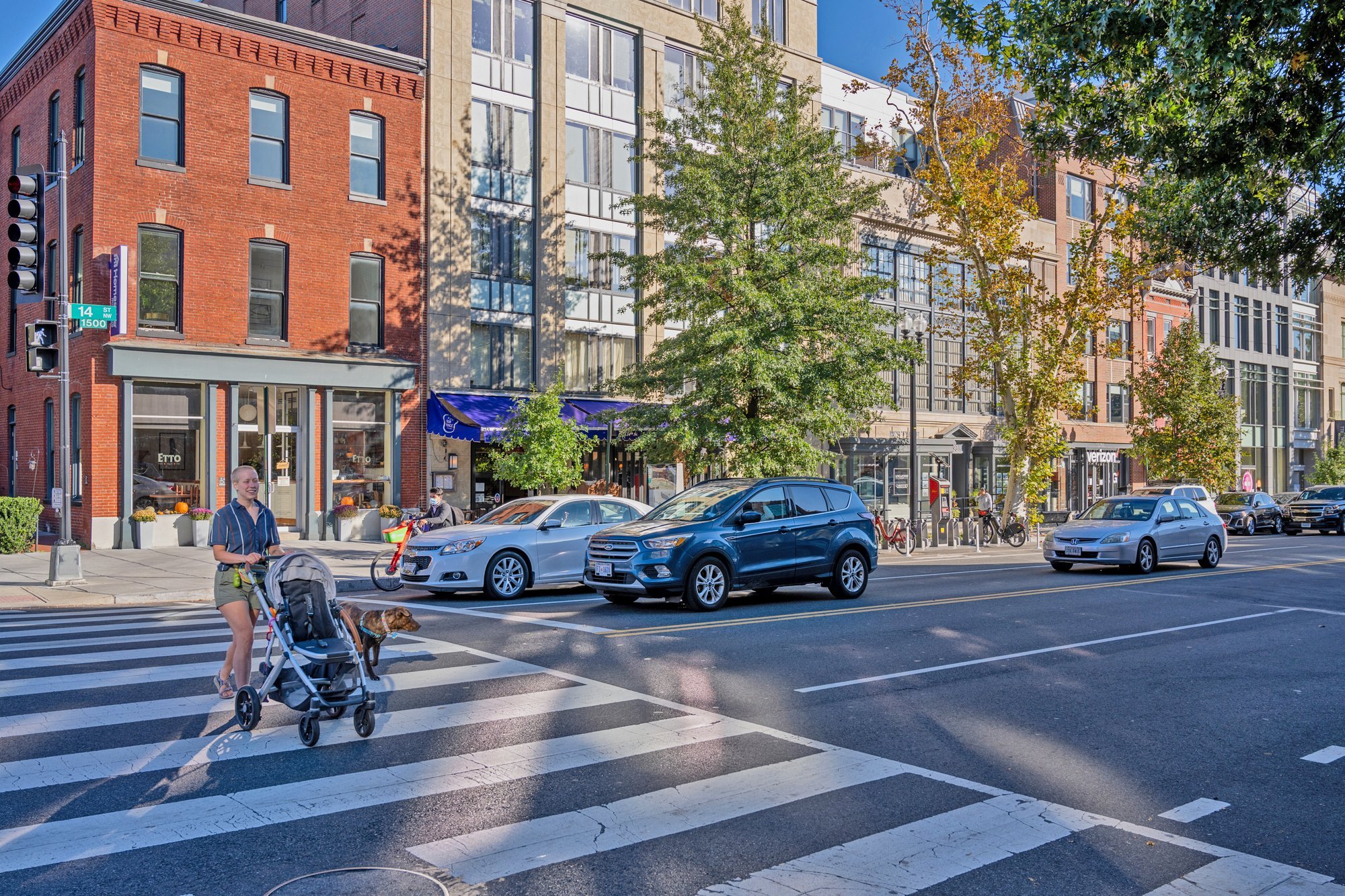 City street scene with pedestrians and cars at a crosswalk.