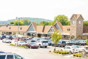 Exterior view of a shopping center with cars in the parking lot.