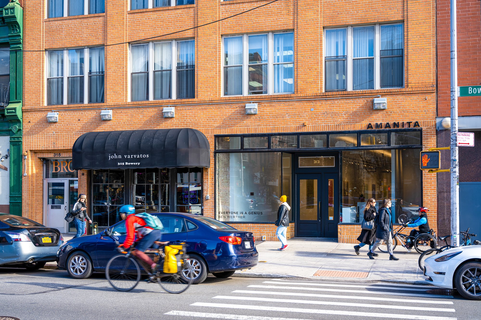 Street-level view of a brick building with shops and pedestrians.