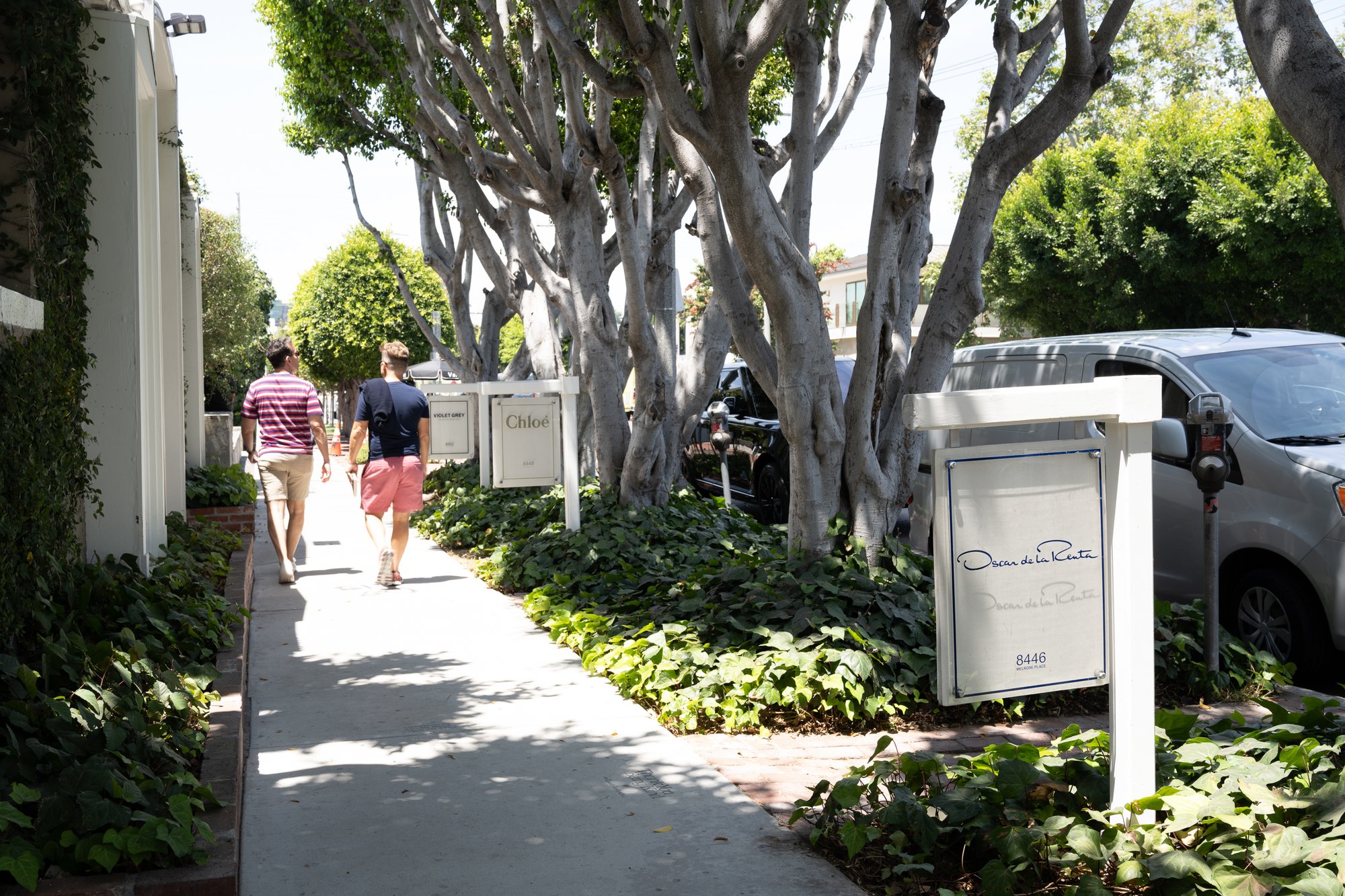 Walkway lined with trees and restaurant signage.