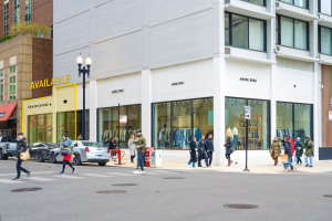 A city street corner with several storefronts and pedestrians.