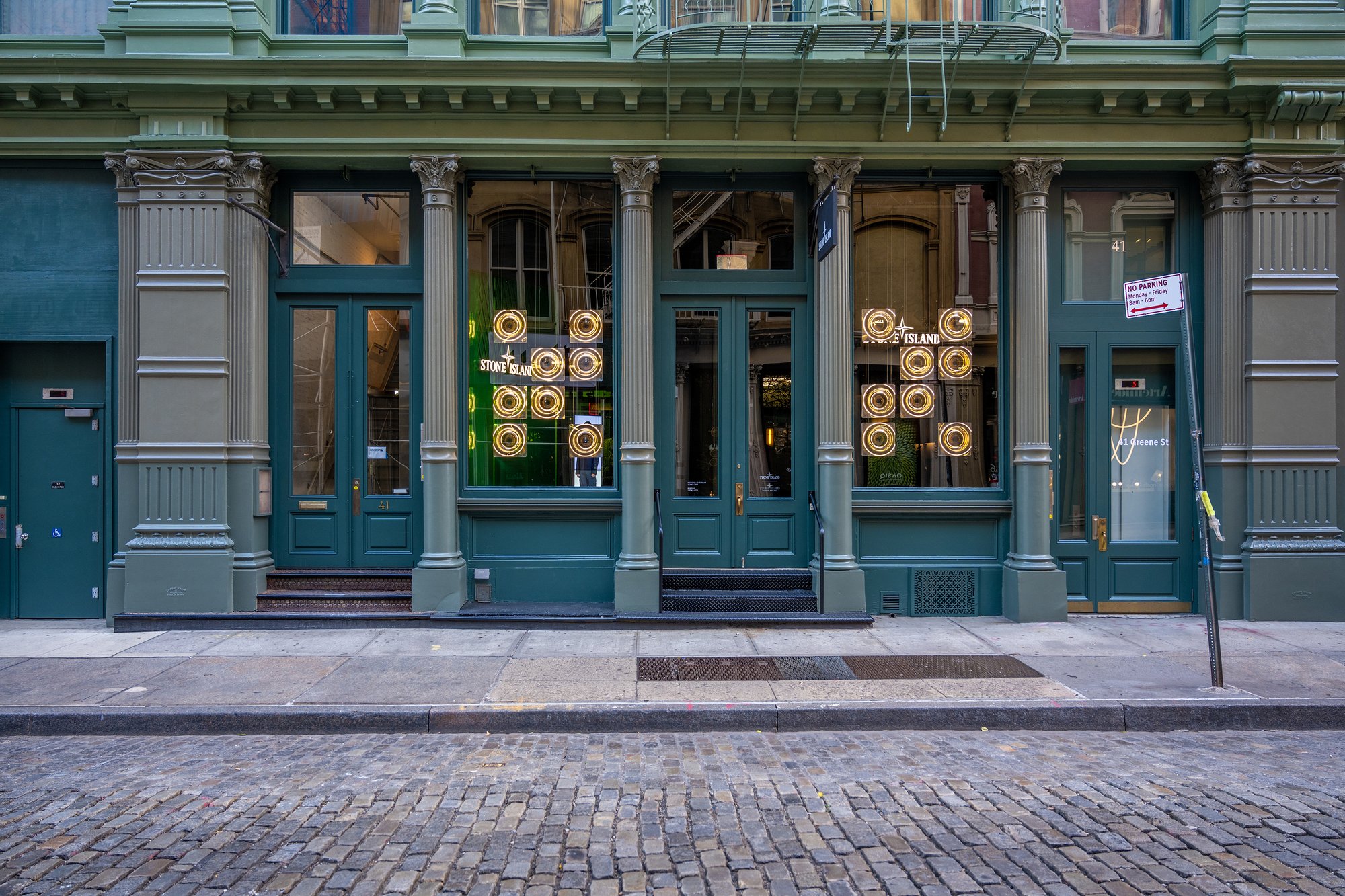 Cast-iron building facade with teal doors and display windows.