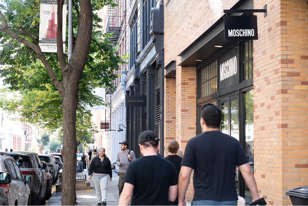People walking past shops on a city street.