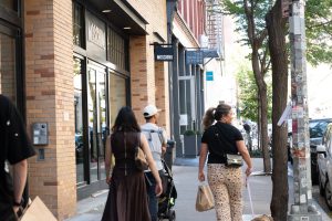 People walking past shops on a city street.