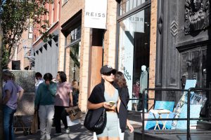 Woman walking past a Reis clothing store.