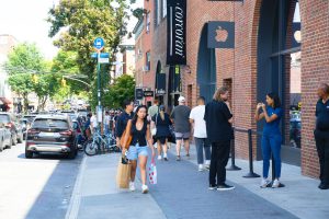 People walking on a city sidewalk in front of an Apple Store.