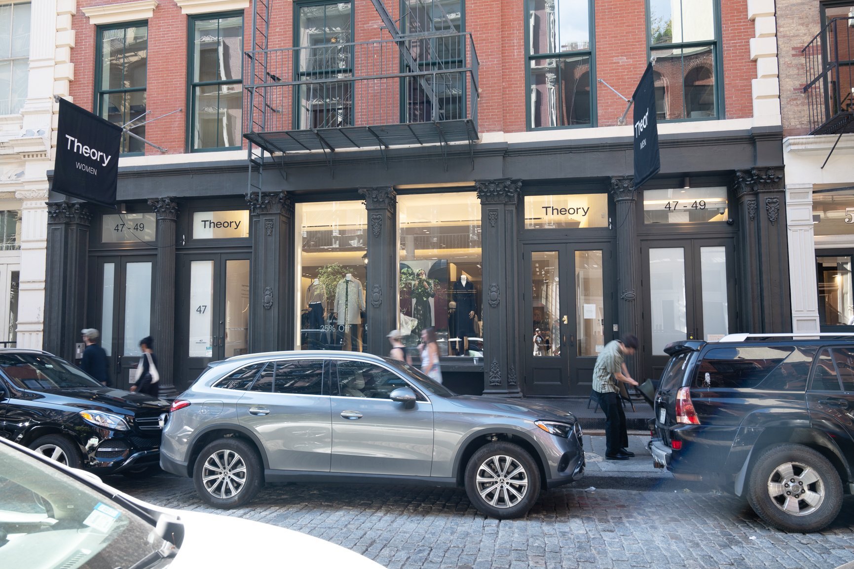 Silver SUV parked in front of a brick building with storefront.