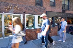 People walking past a brick building with a store called "Alua"