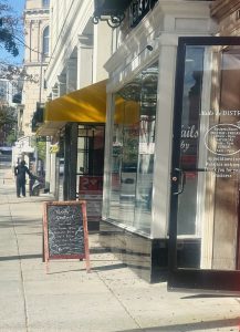 A person walks past a storefront with a chalkboard menu.