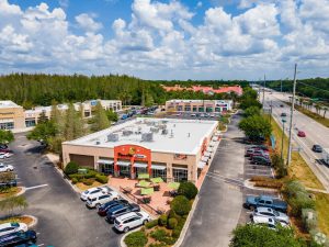 Aerial view of a shopping center with restaurants and parking lot.