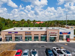 Modern commercial building with several storefronts and parking lot.
