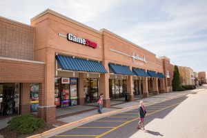 Exterior view of a strip mall with a GameStop store.