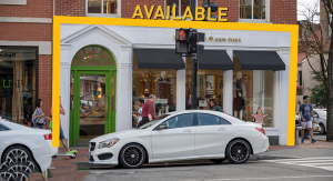 White car parked in front of a store with "AVAILABLE" sign.