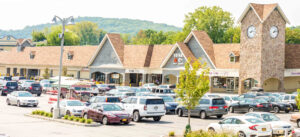 Exterior view of a shopping center with cars in the parking lot.