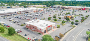 Exterior view of a strip mall with cars in the parking lot.