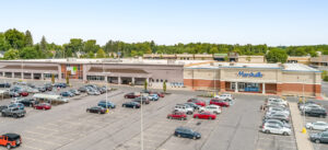 Aerial view of a strip mall with several businesses and a parking lot.