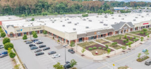 Exterior view of a strip mall with cars in the parking lot.