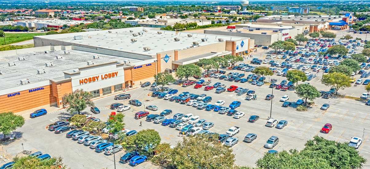 Aerial view of a large retail shopping center parking lot with a Hobby Lobby store.